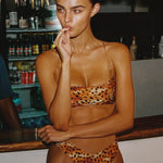 Model wearing a leopard print bikini in a bar setting
