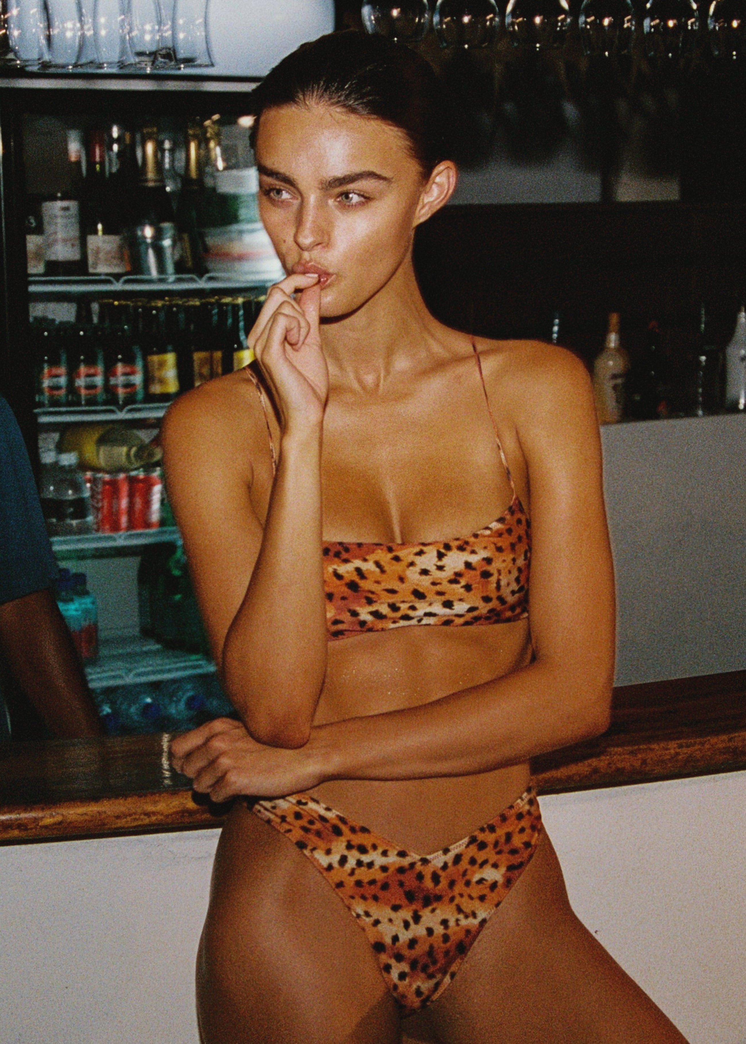 Model wearing a leopard print bikini in a bar setting