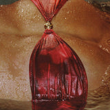 Red leather bag with a gold clasp on a textured surface