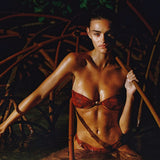 Woman in a red bikini standing in water surrounded by mangrove roots